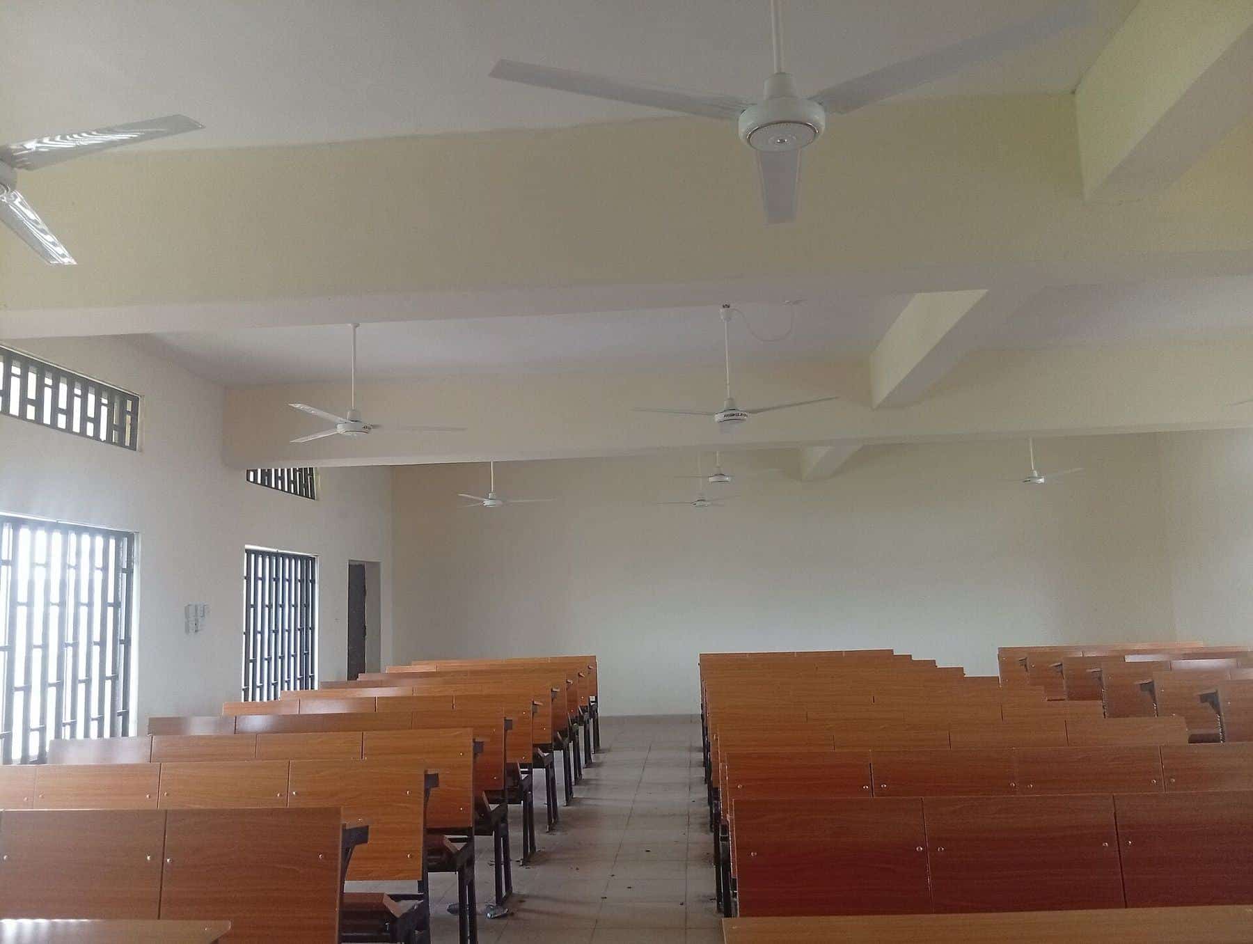 Rows of empty wooden desks in a university lecture theatre